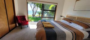 um quarto com uma cama, uma cadeira vermelha e uma janela em Beachfront Bliss - Your Parapara Seaside Retreat em Parapara 