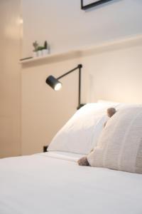 a white bed with a teddy bear in the pillows at PRIME SPOT: Modern Studio+Balcony Darling Harbour in Sydney