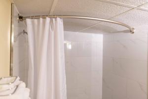 a shower with a white shower curtain in a bathroom at Northern Lights Inn in Fort Saint John