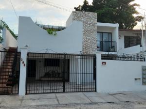 une maison blanche avec un portail avec une grande lettre t dans l'établissement Las Huayitas, by Casa Amaranto, à Mérida