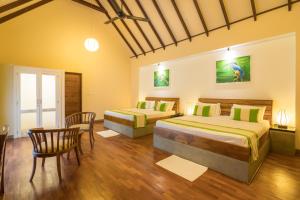 two beds in a room with a table and chairs at Yala Chalets by Lalan Leisure in Kirinda