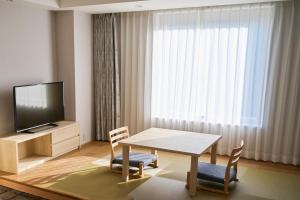 a living room with a table and chairs and a television at Narita Tobu Hotel Airport in Narita
