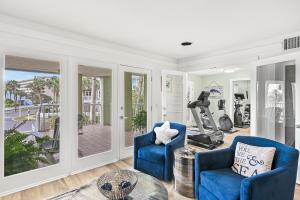 a living room with two blue chairs and a gym at Magnolia House 507 At Destin Pointe Resort in Destin