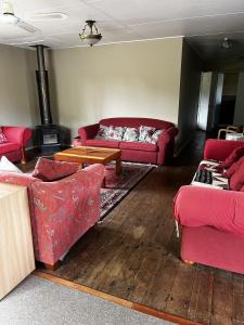 a living room with red couches and a wood stove at Rainbow Mountain cottage in Rotorua