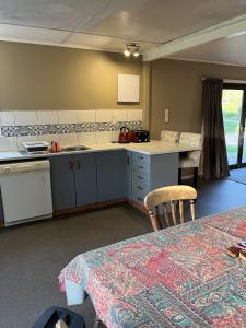 a kitchen with a sink and a counter with a table at Rainbow Mountain cottage in Rotorua