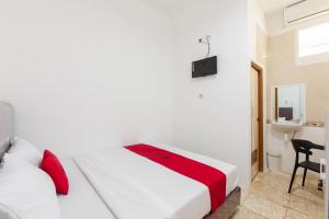 1 dormitorio con cama blanca y manta roja en RedDoorz @ Kemang Dalam, en Yakarta