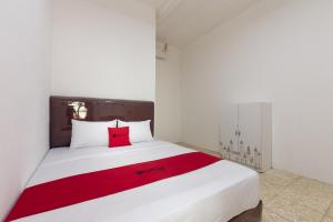 sypialnia z białym łóżkiem i czerwoną poduszką w obiekcie RedDoorz @ Kemang Dalam w Dżakarcie