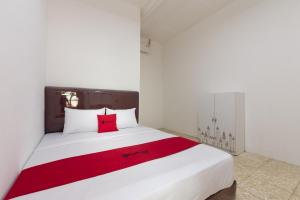 una camera con un letto bianco e un cuscino rosso di RedDoorz @ Kemang Dalam a Giacarta