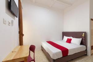 una camera da letto con un letto e una TV a parete di RedDoorz @ Kemang Dalam a Giacarta