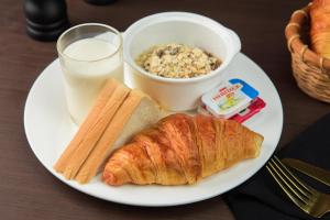 a plate of food with a croissant and a glass of milk at Samnak Lounge in Siem Reap +141 photos