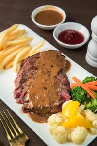 a plate of steak with fries broccoli and sauce at Samnak Lounge in Siem Reap