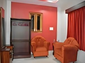 duas cadeiras cor de laranja num quarto com paredes vermelhas em Signature Stay em Port Blair