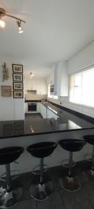 a kitchen with a counter with four bar stools at 703 High Tide, Holiday Apartment, Main Beach, Amanzimtoti in Amanzimtoti
