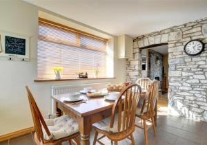 a dining room with a table and a stone wall at Glanhafren in Southerndown