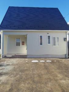 une petite maison blanche avec un toit bleu dans l'établissement 臨湖荘, à Takashima