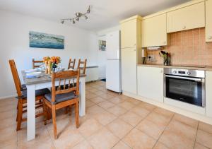 a kitchen with a table and chairs and a refrigerator at 139 Cae Du in Abersoch
