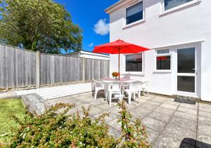 a patio with a table with a red umbrella at 139 Cae Du in Abersoch