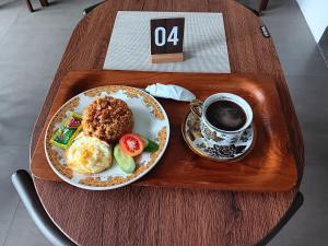 普禾加多的住宿－44 Guest House Syariah，盘子,盘子上放着一盘食物和一杯咖啡