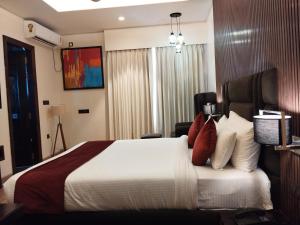 Habitación de hotel con cama con almohadas rojas y blancas en Hotel Prism Jorhat, en Jorhāt