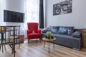 un soggiorno con divano e sedia rossa di CHARLIE - modern centrally located downtown studio a Bratislava