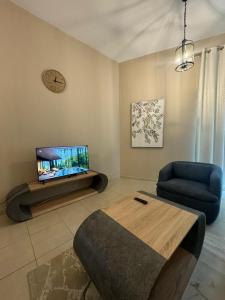 uma sala de estar com uma televisão, um sofá e uma mesa em Marbella Grand Holiday Homes - Al Nahda 1 no Dubai