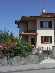 une maison blanche avec des fleurs roses devant elle dans l'établissement Casa Roberta, à Cavriglia