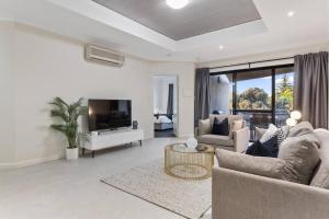 a living room with a couch and a tv at Luxury Retreat in the Heart of Subiaco in Perth