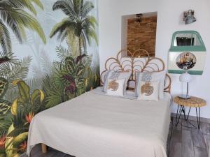 a bed in a room with a tropical wall at Loft Cosy " Le Flamant Rose " in Fréjus