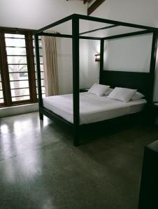 una camera con letto a baldacchino e lenzuola bianche di Mount Bliss Retreat a Mount Lavinia