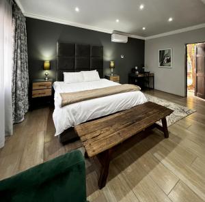 ein Schlafzimmer mit einem großen Bett und einem Holztisch in der Unterkunft Ferns Country Lodge in Mahikeng