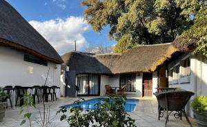 a house with a thatched roof and a swimming pool at Ferns Country Lodge in Mahikeng