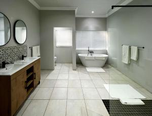 La salle de bains est pourvue de 2 lavabos et d'une baignoire. dans l'établissement Ferns Country Lodge, à Mahikeng