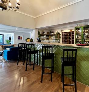 bar w salonie z czarnymi stołkami barowymi w obiekcie Ferns Country Lodge w mieście Mahikeng