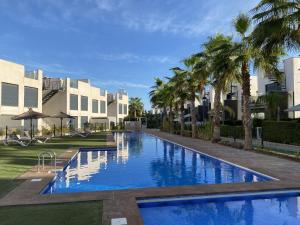 a swimming pool with palm trees in front of condos at Villa Tindra in Torrevieja