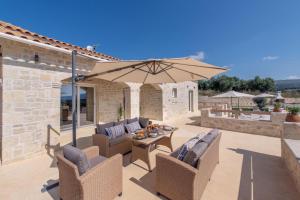 un patio con mesa y sombrilla en Villa Niragia with Magnificent view, en Astérion