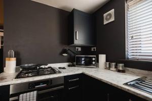a black kitchen with a stove and a microwave at Hullidays》Old Town Luxury Cavern in Hull +7 photos