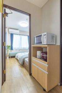 Habitación con cama y microondas en un armario. en Bright Modern Airbnb in Tokyo's Northern District, en Tokio