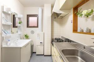 cocina blanca con fregadero y fogones en Bright Modern Airbnb in Tokyo's Northern District, en Tokio