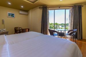 a bedroom with a white bed and a table and chairs at Blue Wave Hotel Maldives for SURF, FISHING and Beach in Kudahuvadhoo