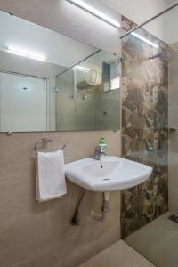 ein Bad mit einem Waschbecken und einer Glasdusche in der Unterkunft Westside Hotel Gachibowli in Hyderabad