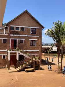 a large brick building with a staircase in front of it at Chambres d'hôtes du lycée Picot de Clorivière dont les revenus financent l'éducation des élèves in Antsirabe
