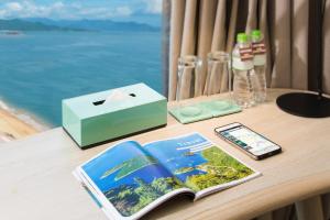 a table with a book and a cell phone and a box at Liberty Central Nha Trang Hotel in Nha Trang