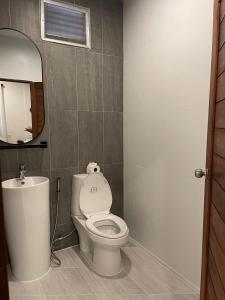 a bathroom with a toilet and a sink and a mirror at V-View Beach Resort in Baan Tai