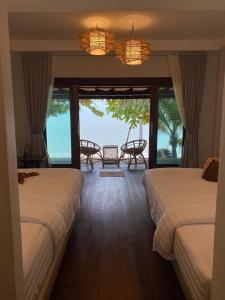 two beds in a room with a view of the ocean at V-View Beach Resort in Baan Tai