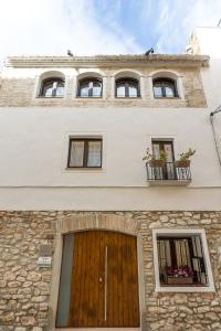a building with three windows and a wooden door at Casa Santiago casa rural in Tivenys