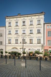 un gran edificio blanco con mesas y sombrillas en Hotel-Gasthof Höttl en Deggendorf