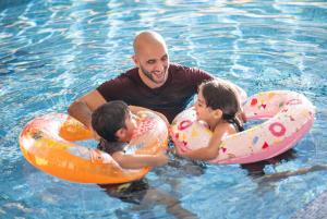 un hombre y dos niños en inflables en el agua en Delta Hotels by Marriott City Center Doha, en Doha