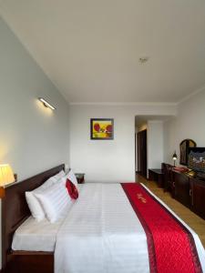 1 dormitorio con 1 cama blanca grande con manta roja en Đông Xuyên Hotel en Long Xuyên