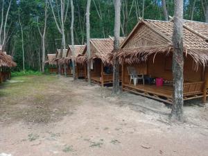 a row of wooden huts in a forest at Pitt Bungalow in Ko Lanta