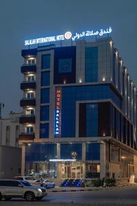 Salalah International Hotel في صلالة: مبنى كبير فيه سيارات تقف امامه